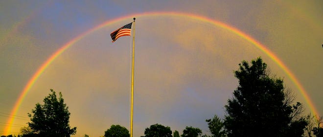 A rainbow forms over the American flag during a rainstorm passing over the north side of Peoria on Saturday.