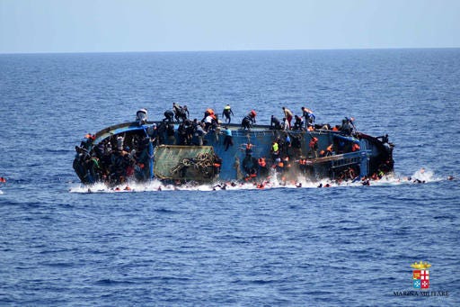 FILE - In this May 25, 2016 file photo made available by the Italian Navy, people try to jump in the water right before their boat overturns off the Libyan coast. Over 700 migrants are feared dead in three Mediterranean Sea shipwrecks south of Italy in the last few days as they tried desperately to reach Europe in unseaworthy smuggling boats, the U.N. refugee agency said Sunday, May 29, 2016. (Italian navy via AP Photo, file)