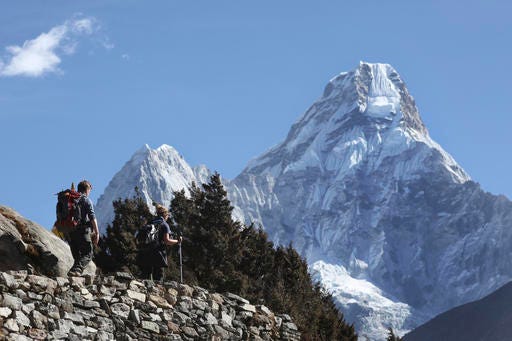 FILE - In this Feb. 19, 2016, file photo, trekkers make their way to Dingboche, a popular Mount Everest base camp, in Pangboche, Nepal. Nepal celebrated Everest Day on Sunday, May 29, 2016, by honoring nine Sherpa guides who fixed ropes and dug the route to the summit so hundreds of climbers could scale the world’s highest mountain this month, following two years of disasters. (AP Photo/Tashi Sherpa, File)