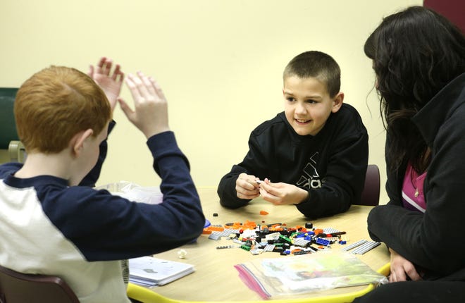Jared Frank (left) cheers as his Lego creation takes form. Colin Schmidt is in charge of finding the right pieces for the construction ove seen by staff member Liz Jeffery during the Golden Key Center for Exceptional Children's Lego Therapy program. (CantonRep.com / Bob Rossiter)
