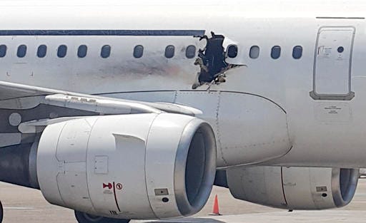 FILE - In this Tuesday, Feb. 2, 2016 file photo, of a hole in a plane operated by Daallo Airlines as it sits on the runway of the airport in Mogadishu, Somalia. A military court in the Somali capital has given life terms Monday, May 30, 2016 to two men convicted of masterminding the bombing in February of the airliner which made an emergency landing with a gaping hole in its fuselage. (AP Photo, File)