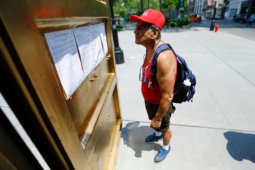In a Friday, May 27, 2016 photo, Joe Martinez reads over information about a container outfitted with video conference electronics that is part of an art installation at Military Park in downtown Newark, N.J. The portal allows people inside a container to communicate to people in containers in other cities across the world. (AP Photo/Julio Cortez)