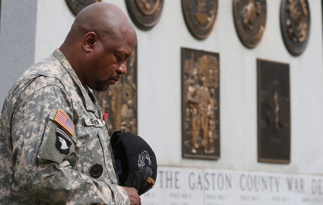 Veteran Steve Garvin bows his head as the invocation is given during the Memorial Day program held at Gaston Memorial Park. (Mike Hensdill/The Gazette)
