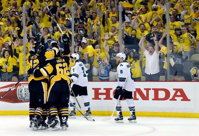 Pittsburgh Penguins' Ben Lovejoy (12) and Carl Hagelin (62) swarm Nick Bonino after his game-winning goal against the San Jose Sharks during the third period in Game 1 of the Stanley Cup final series Monday, May 30, 2016, in Pittsburgh.