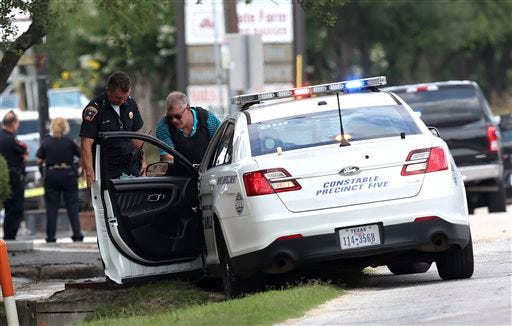 A C=constable car with a shot-out window remains at the scene where Houston police were investigating a shooting, Sunday, May 29, 2016, in Houston. A man came into an auto detail shop and began shooting, killing a man known to be a customer and putting a neighborhood on lockdown before being killed by a SWAT officer, police said. Several people were shot and injured. (Elizabeth Conley/Houston Chronicle via AP)