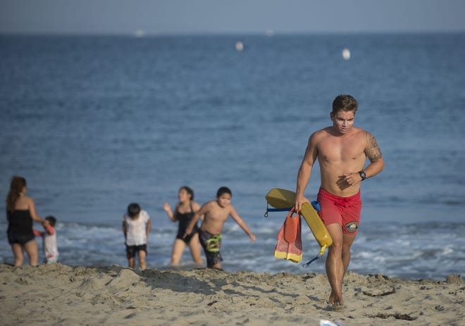 A lifeguard warns beach goers to stay out of the water Sunday at Corona del Mar beach in Newport Beach, Calif. Thousands of Memorial Day beachgoers were kept out of the water Monday as lifeguards searched miles of popular Southern California shoreline for a shark they believe attacked a swimmer the day before. (Cindy Yamanaka/The Orange County Register via AP)