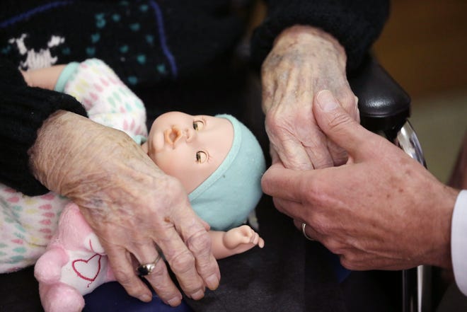 FILE - In this April 14, 2016, file photo, a son holds his mother's hand at her nursing home in Adrian, Mich. Long-term care grew more expensive again in 2016, with the median annual bill for a private nursing home room edging closer to $100,000, according to a survey released Tuesday, May 10, 2016, from Genworth Financial. (AP Photo/Carlos Osorio, File)