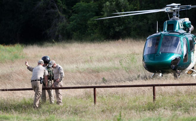 The pilot and co-pilot speak with a Texas Parks & Wildlife department game warden Friday morning, June 3, 2016, before joining in the search efforts of 6 missing soldiers from Fort Hood, Texas. (Rusty Schramm/The Temple Daily Telegram via AP) MANDATORY CREDIT