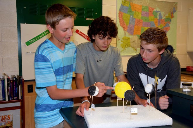 (File) Enjoying last year's Medford Science Summit are (from left) Cameron Foster, Jake Kozmor and C.J. Kane, who are discussing a model made by classmate Madison McGehrin that shows seasonal changes. For the second year, the Medford Memorial Middle School is hosting the event, to be held on Saturday.