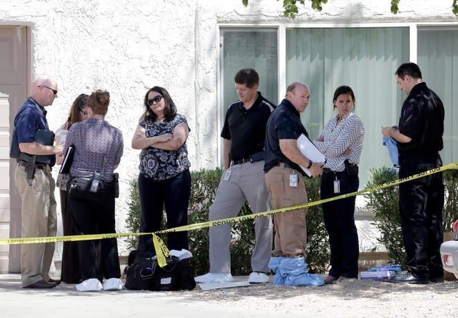 Law enforcement officials stand outside a home Thursday in Phoenix where three boys were killed during a several hour period Wednesday night. The boy's mother was hospitalized in critical condition with self-inflicted stab wounds according to Phoenix police.
