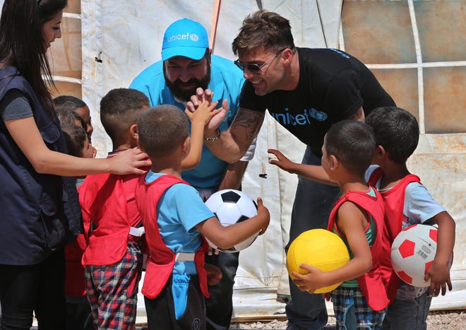 In this picture taken on Thursday, Ricky Martin, right, the world-renowned singer and UNICEF goodwill ambassador, cheers with Syrian children during his visit to an informal Syrian refugee camp, in Minnieh, near the northern city of Tripoli, Lebanon. He said that the word "refugee" had lost its value but that the international community should "open its heart."