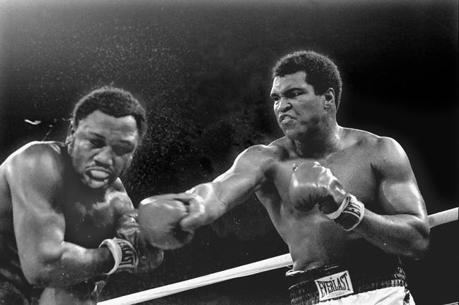 In this Oct. 1, 1975, file photo, spray flies from the head of challenger Joe Frazier as heavyweight champion Muhammad Ali connects with a right in the ninth round of their title fight in Manila, Philippines. Ali, the magnificent heavyweight champion whose fast fists and irrepressible personality transcended sports and captivated the world, has died according to a statement released by his family Friday, June 3, 2016. He was 74. THE ASSOCIATED PRESS
