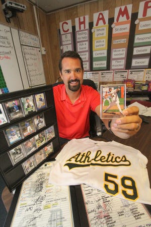 Andrew Brown, a former Major League Baseball pitcher, holds one of his baseball cards with other memorbilia from his days on the mound. He's now a math teacher at Starke Elementary School in DeLand. News-Journal/David Tucker
