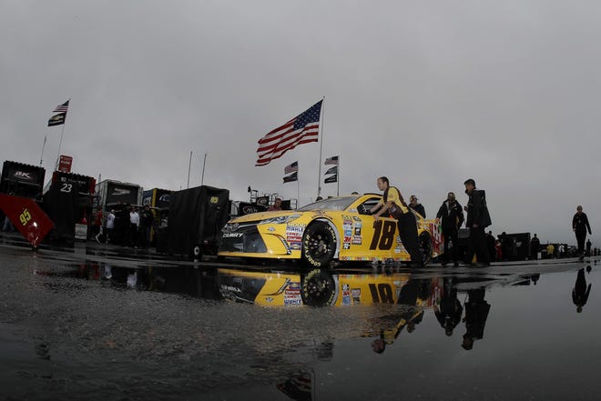 Crew members push the car of Kyle Busch in the garage area before the NASCAR Sprint Cup series auto race, Sunday, June 5, 2016, in Long Pond, Pa. (AP Photo/Matt Slocum)