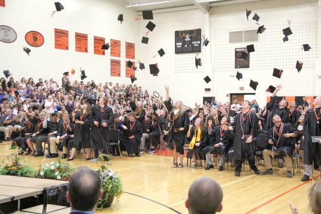 Graduates at Jonesville High School toss their caps in the air celebrating the end of their high school career Sunday. ANDY BARRAND PHOTO