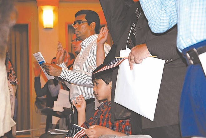 A young boy attempts to say the Naturalization Oath of Allegiance. Photo by Naomi Whidden / The Daily News