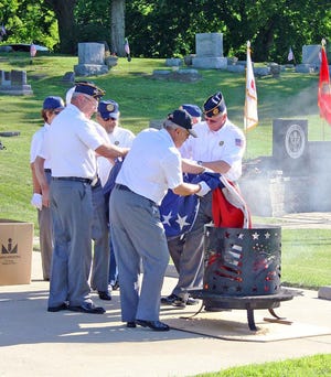 The Jonesville American Legion Post 195 ceremoniously lower a larger, damaged American flag into one of the burn pits during the 2015 ceremony. COURTESY OF KEVIN MURRAY