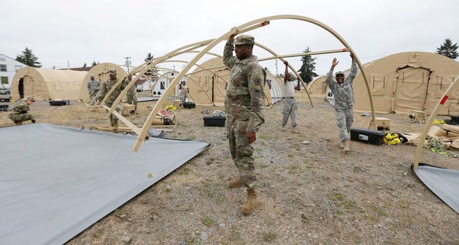 In this May 24, 2016 file photo, soldiers work to assemble temporary living structures at Joint Base Lewis-McChord in Washington state that will be used by troops taking part in a massive earthquake and tsunami readiness drill overseen by the Federal Emergency Management Agency on June 7-10, 2016. The four-day event, called Cascadia Rising, begins Tuesday. (AP Photo/Ted S. Warren, File)
