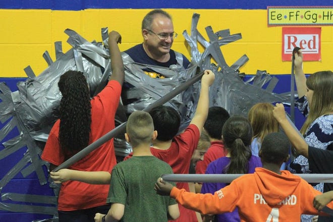 Havelock Elementary School Principal Christopher Germain gets taped to the wall by his students Tuesday to fulfill his end of a bargain for the children making improvements on their end-of-grade testing. Wednesday marked the last day of classes for Craven County students.