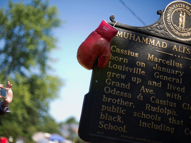Boxing gloves hang on a historical marker outside the childhood home of Muhammad Ali Thursday, June 9, 2016, in Louisville, Ky. Ali's memorial service Friday looms as one of the most historic events in Louisville's history.
