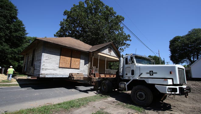 A crew from Simmons House Moving works to move a Loray Village house from one side of Vance Street to the other side Friday morning. PHOTO MIKE HENSDILL/THE GAZETTE