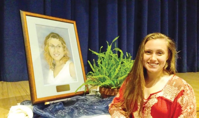 Kyra Young, a member of the Class of 2016 at Leominster High School, stands next to her portrait of LHS teacher Michele Oshman, who passed away in April.