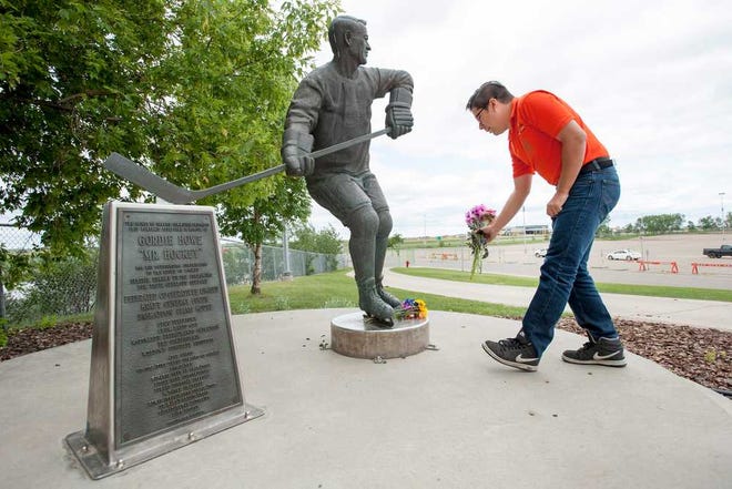 Matt Adamowski lays flowers at a statue of Gordie Howe at the Sasktel Centre in Saskatoon, Saskatchewan, Friday, June 10, 2016. Gordie Howe, the hockey great who set scoring records that stood for decades, has died. He was 88. Son Murray Howe confirmed the death Friday, June 10, 2016, texting to The Associated Press: "Mr Hockey left peacefully, beautifully, and w no regrets."(Liam Richards/The Canadian Press via AP)
