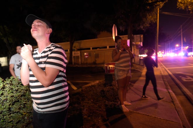 Brandon Shuford, left, waits down the street from the scene of a shooting involving multiple fatalities at a nightclub in Orlando, Fla., Sunday, June 12, 2016. (AP Photo/Phelan M. Ebenhack)