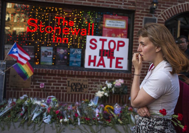 A woman cries and holds flowers in front of a makeshift memorial in New York City to remember the victims of the mass shooting in Orlando, Florida.