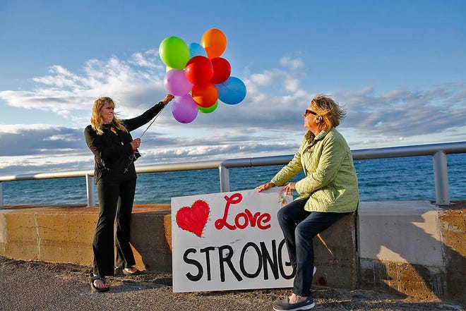 Debbie McCarthy and Ginny Winnette of Hull, both parents of gay children, release some rainbow-colored balloons at a Hull vigil Sunday, June 12, 2016, in memory of those killed at a Florida nightclub.