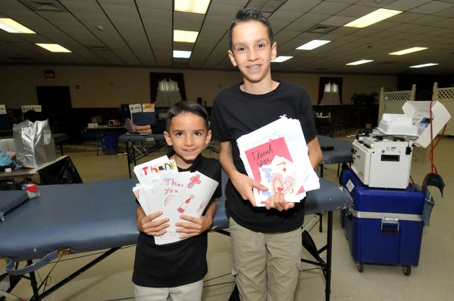 Vincent Contratti, 8, and his brother, Alex, 12, of Burlington Township, hold thank-you notes to give blood donors at the Relief Fire Company No. 3 station in Burlington Township.