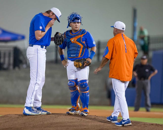 Florida coach Kevin O'Sullivan approaches the mound to talk with Florida catcher Mike Rivera (4) and pitcher A.J. Puk after Puk walks the first two batters to start the first inning in Game 3 of NCAA college baseball tournament super regional against Florida State in Gainesville, Fla., on Monday, June 13, 2016. (AP Photo/Ronald Irby)