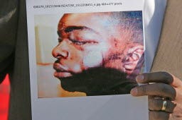 An activist displays a photo of Joshua Robinson during a 2013 news conference outside Providence police headquarters.