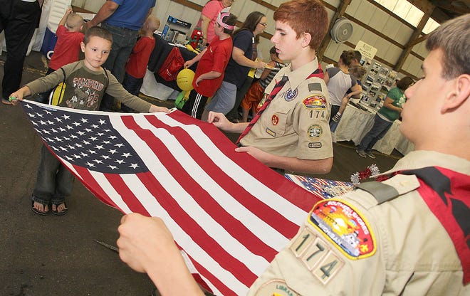 Tristen Strodtman, (right) and Sam Beach members of Boy Scout Troop 174 teach Eliot Flaugher, of Manistee, how to fold the American Flag at Kids Fest. Flaugher and his sister Alivia were visiting their grandparents. ANDY BARRAND PHOTO