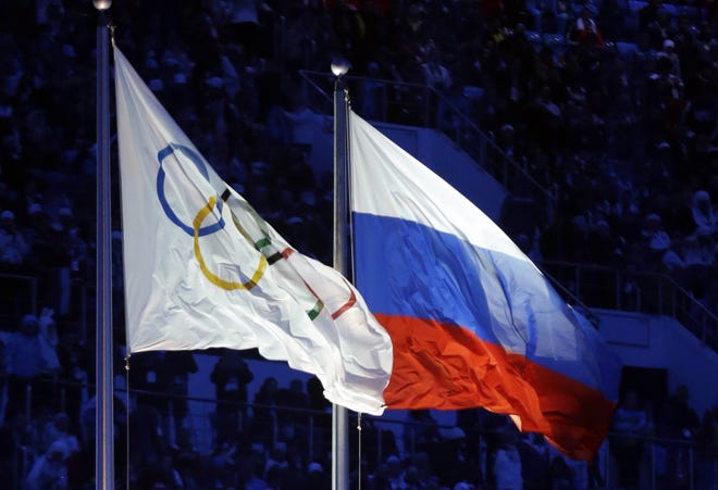 In this Feb. 7, 2014 file photo the Russian and the Olympic flags wave during the opening ceremony of the 2014 Winter Olympics in Sochi. Track and field's world governing body decides Friday whether to uphold or lift its ban on Russian athletes ahead of the Rio de Janeiro Olympics. Associated Press File/Patrick Semansky