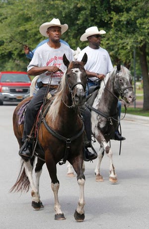 Virgil Roberts and Daryl Watkins ride along in Riverwalk Park in Jacksonville during the 2014 Juneteenth celebration.