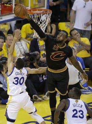 Cavaliers' LeBron James, top, blocks a shot by Warriors' Stephen Curry (30) during the first half of Game 7. The Associated Press