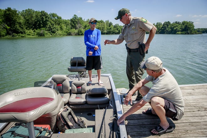 Illinois Conservation Police Officer Kevin Bettis, center, goes through a safety check with Dan Drewes, of Chatham, Ill., and his grandson, Griffin Harms, at boat launch on Sangchris Lake State Park, Friday, June 17, 2016, southeast of Rochester, Ill. Illinois boaters are required to have certain safety items on board at all times including flotation devices, a whistle and a fire extinguisher. Justin L. Fowler/The State Journal-Register