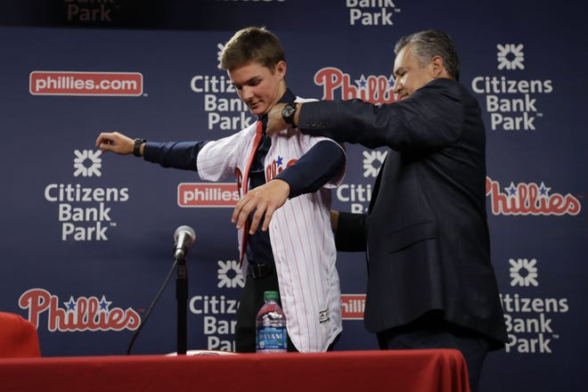 Mickey Moniak, the Philadelphia Phillies' first overall selection in 2016 MLB draft, puts on a jersey with help from Johnny Almaraz, Phillies Director of Amateur Scouting at a news conference at Citizens Bank Park on Tuesday, June 21, 2016, in Philadelphia.