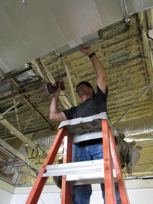 Ed Kellum of Montefusco HVAC installs air conditioning vents in the administrative section of the Holeman Center for Career and Technical Education Building.