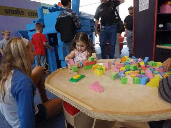 Kennedy Lang, 2, plays with blocks during an event at the Kansas Children's Discovery Center. Her sister Cidney, 13, left, helped keep an eye on the younger children.
