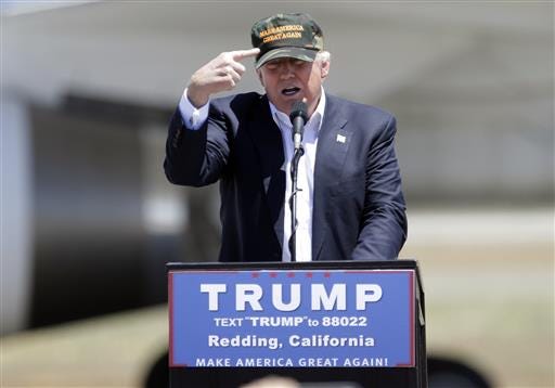 Republican presidential candidate Donald Trump gestures to a his camouflaged "Make America Great" hat at a campaign During rally at the Redding Municipal Airport in Redding, Calif. Trump's campaign bought the hats from a company in Lafayette, La.