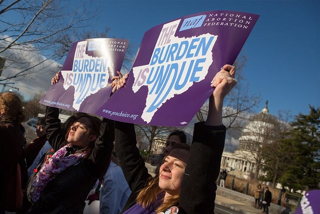Lauren Baker, right, and Mary Baumgard hold signs in front of the U.S. Supreme Court on March 2 as the court argues a case on a Texas abortion law.