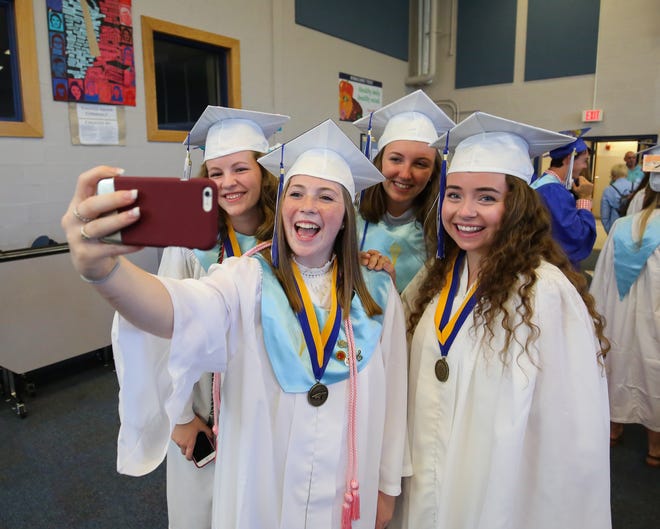 Rachel Laroche takes a, "selfi" with her friends Lizzy Baker, Caitlyn Barbieri and Savannah McMenemy prior to the start of the Winnacunnet Class of 2016 graduation ceremony on Saturday. Photo by Matt Parker
