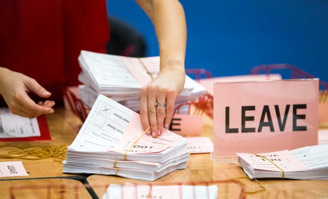 A teller counts ballot papers at the Titanic Exhibition Centre in Belfast, Northern Ireland, after polls closed in the EU referendum Thursday, June 23, 2016. Britain's referendum on whether to leave the European Union was too close to call early Friday, with increasingly mixed signals challenging earlier indications that "remain" had won a narrow victory.