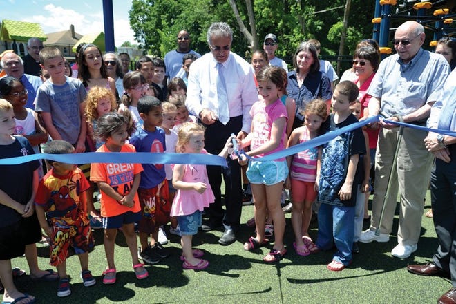Sisters Lilliana Freda, 3, and Riley Aldert, 9, both of Leominster, cut the ribbon to officially open the expanded and upgraded Louis Charpentier Playground.