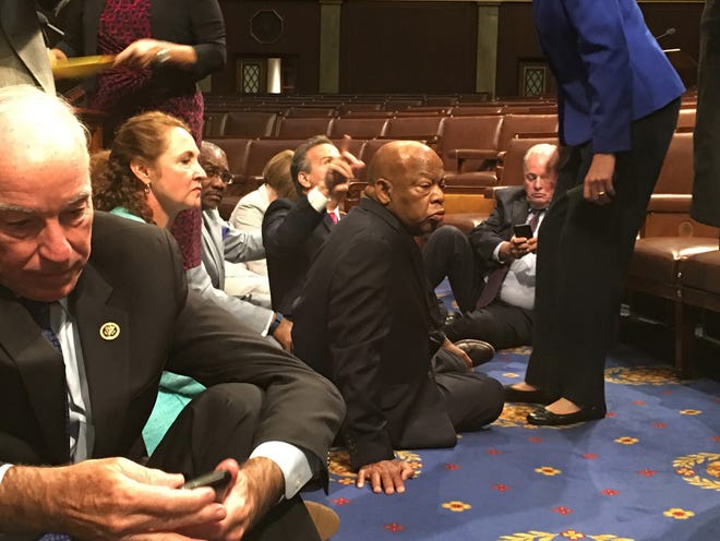 In this photo provided by Rep. John Yarmuth, D-Ky., Democratic members of Congress, including Rep. John Lewis, D-Ga., center, and Rep. Joe Courtney, D-Conn., left, participate in sit-in protest on the floor of the House on Capitol Hill in Washington on Wednesday, June 22, 2016 seeking a vote on gun control measures. (Rep. John Yarmuth via AP)