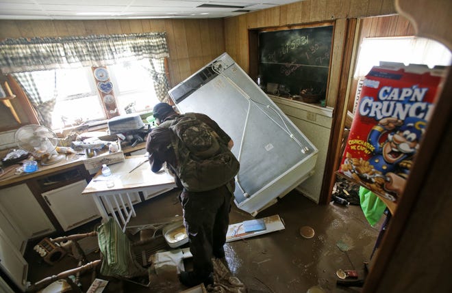 West Virginia Natural Resources police officer Chris Lester searches a flooded home in Rainelle, W. Va., Saturday, June 25, 2016. Heavy rains that pummeled West Virginia left multiple people dead, and authorities said Saturday that an unknown number of people in the hardest-hit county remained unaccounted for. (AP Photo/Steve Helber)