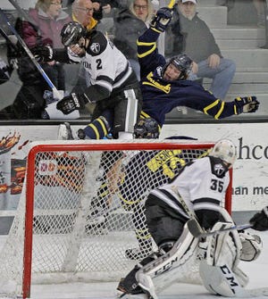 PC's Vinny Desharnais (2) knocks down a Merrimack player during a Hockey East playoff game on March 12.
