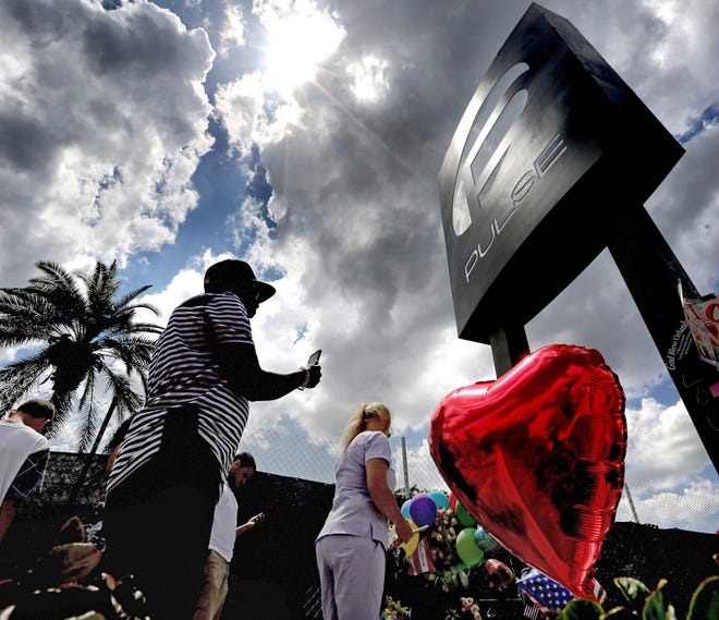 Visitors pay their respects at a memorial in front of the Pulse nightclub in Orlando on Thursday. (Joe Burbank/Orlando Sentinel via AP)